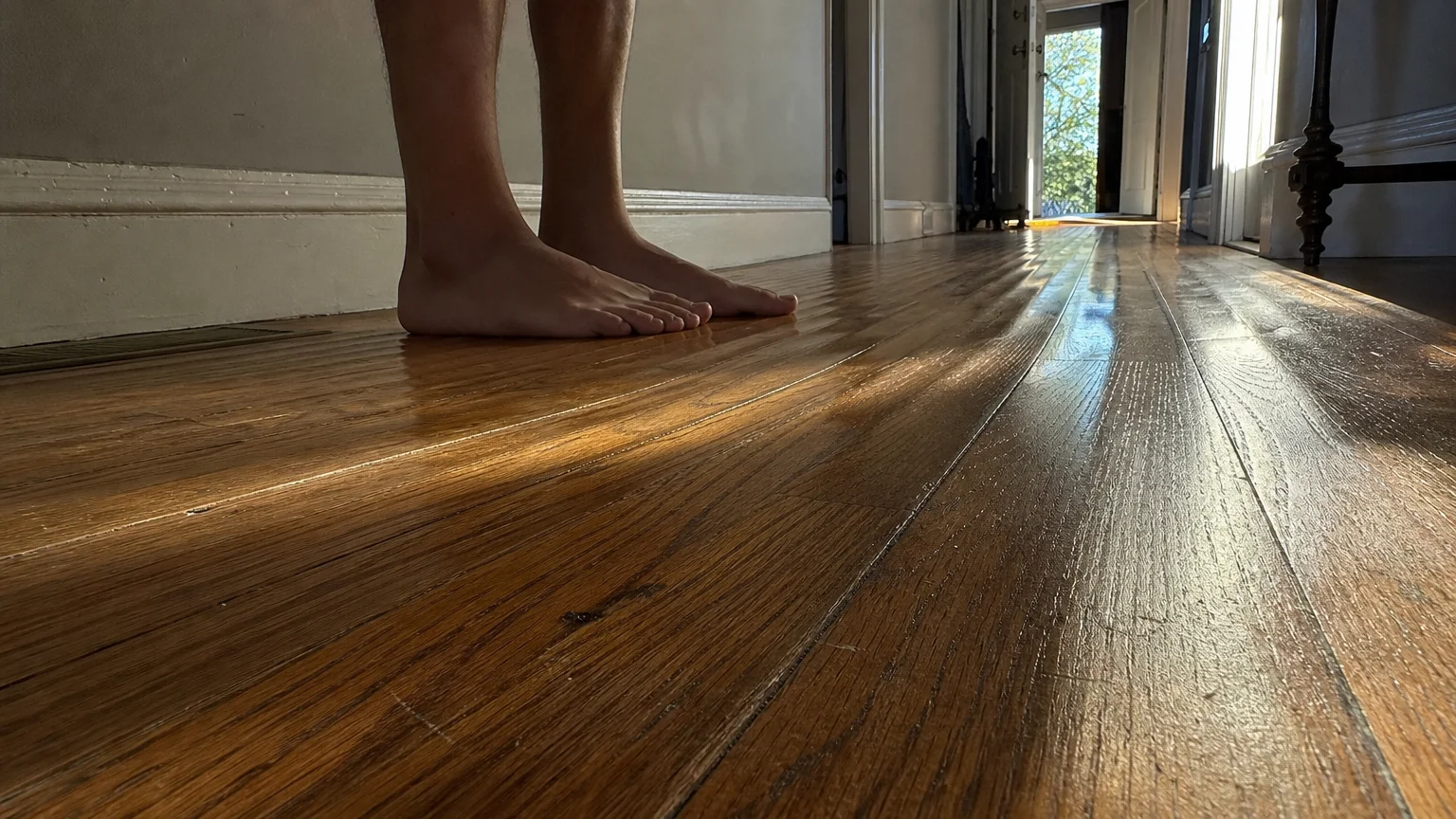 A low-angle photo looking across a wavy, moisture-damaged hardwood floor, showing deep ridges and distorted planks.